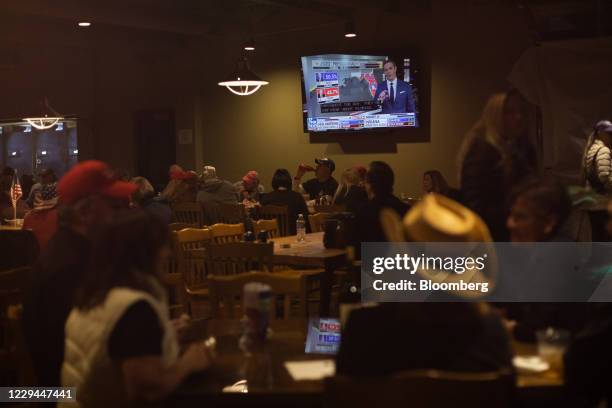 Attendees watch election results come in during a 2020 U.S. Presidential election night 'Trump Re- Election' watch party at Huron Valley Guns in New...