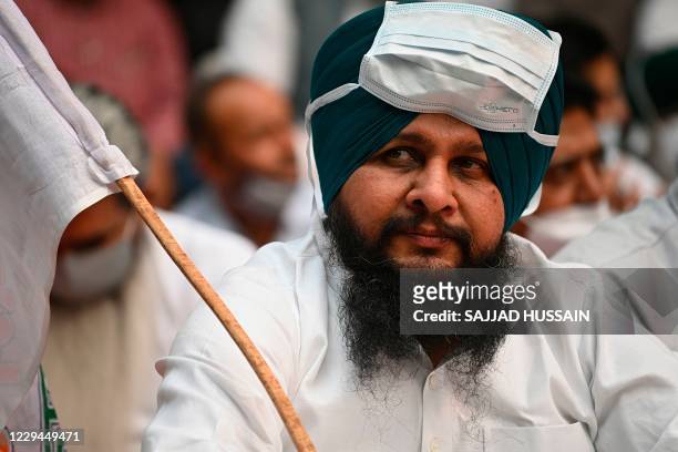 Man wearing a facemask on his forehead listens to Punjab state chief minister Amarinder Singh during a protest against the recent passing of...