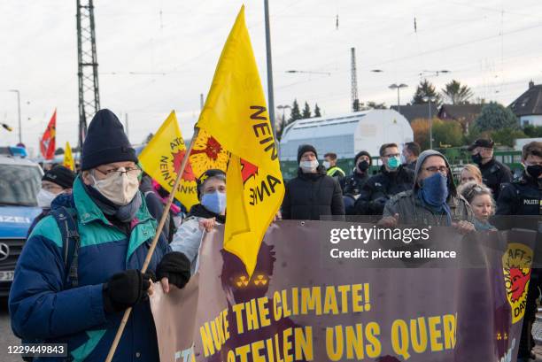November 2020, Hessen, Biblis: Anti-nuclear opponents protest with flags and the inscription "Atomkraft nein danke" next to policemen at the train...