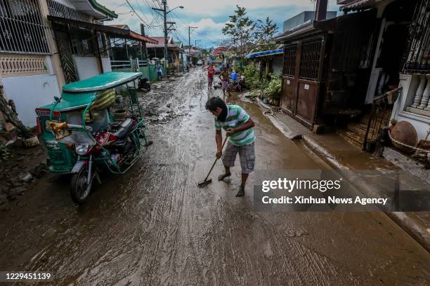 Nov. 2, 2020 -- A man cleans a road covered with mud and debris after a flood triggered by heavy rains from Typhoon Goni in Batangas Province, the...