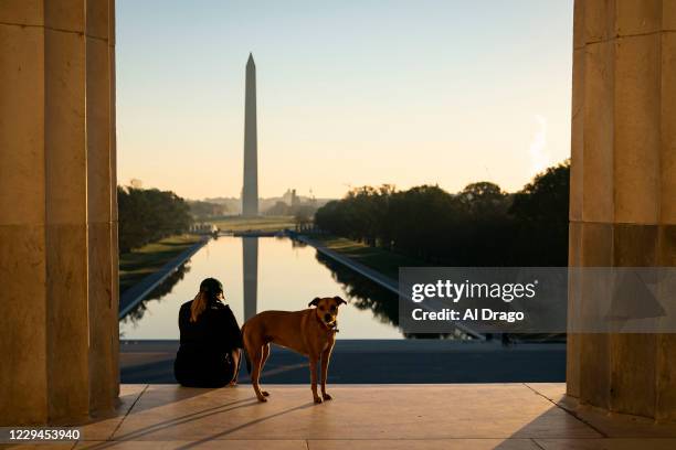 Woman and her dog watch the sun rise on the steps of the Lincoln Memorial on November 4, 2020 in Washington, DC. After a record-breaking early voting...