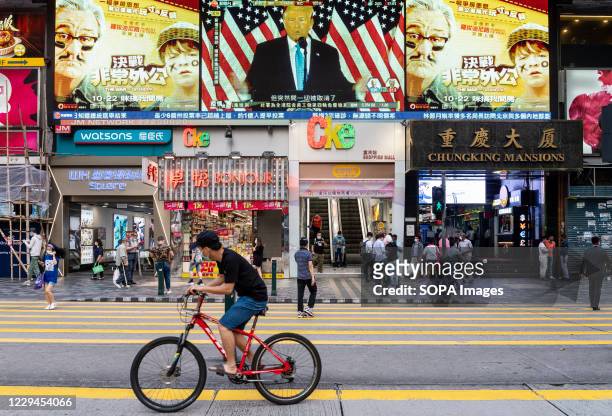 Pedestrians cross the street at a zebra crossing as Republican candidate Donald J. Trump speaks during a live news report about the US presidential...