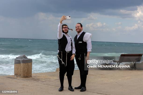 Ultra-Orthodox Jewish men take a 'selfie' photograph on the shore near the Israeli coastal city of Ashdod on a stormy day, on November 4, 2020.