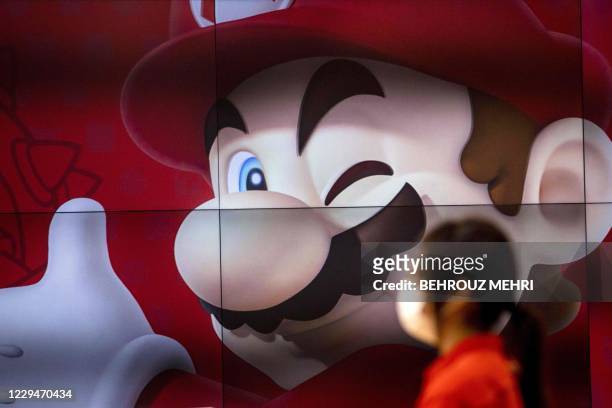 An employee stands next to a screen displaying Nintendo game character Mario at a Nintendo store in Tokyo on November 5 after the gaming giant said...