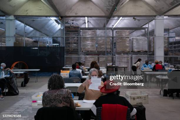 Election officials wearing protective masks count military absentee ballots for the 2020 Presidential election at the Dekalb County Voter...