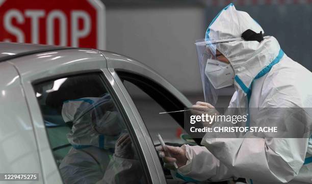 Medical staff takes a swab sample at a drive-through COVID-19 test centre in Memmingen, southern Germany, on November 5 amid the novel coronavirus...