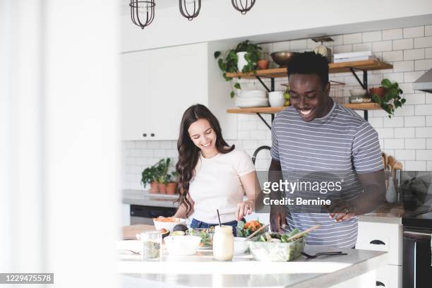 young couple cooking in bright kitchen - couple cooking photos et images de collection