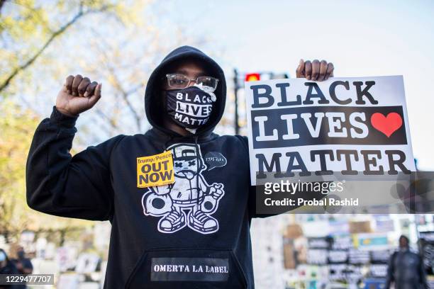 Protestor holding a sign with Black Lives Matter written on it, stands at Black Lives Matter Plaza near the White House while waiting for the final...