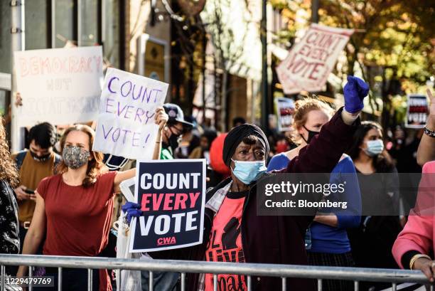 Demonstrators wearing protective masks hold "Count Every Vote" signs at a protest in front of the Convention Center during the 2020 Presidential...