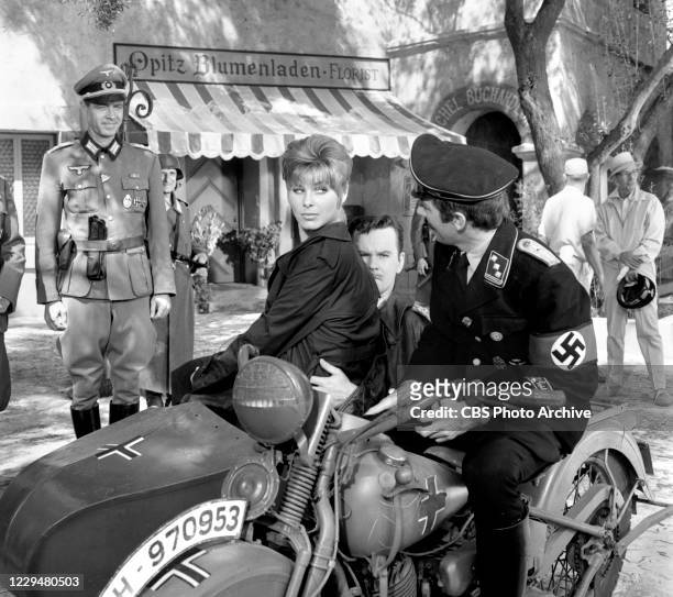 Pictured from left on motorcylce are actors Jayne Massey sitting on Bob Crane's lap and Richard Dawson in the HOGAN'S HEROES episode, "The...