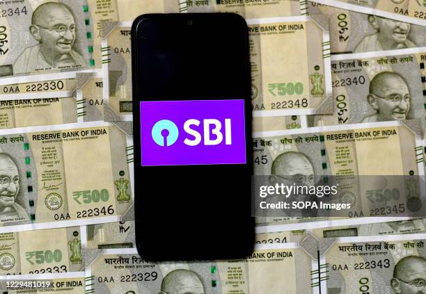 In this photo illustration, State Bank of India Logo seen displayed on a smart phone on the background of Indian Currency note illustrations.