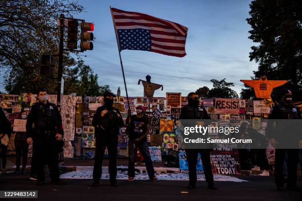 Woman waves an upside down American flag as people gather at Black Lives Matter Plaza as they wait for the results of the presidential election...