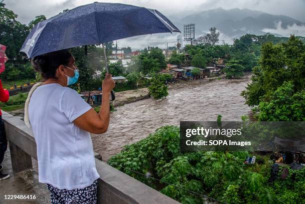 People gather on a bridge to watch the overflowing Rio Blanco river during the aftermath. At least one death, 379 homes destroyed and more than 2,000...