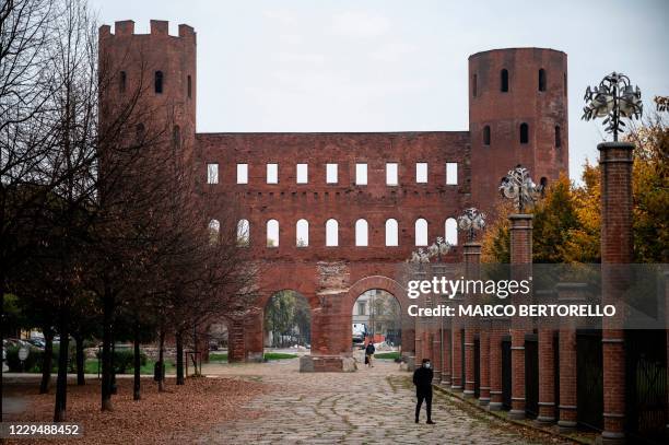Man wearing a face mask walks near the Porta Palatina in Turin, on November 6, 2020 after the new local lockdown in Piedmont Region, northwestern...