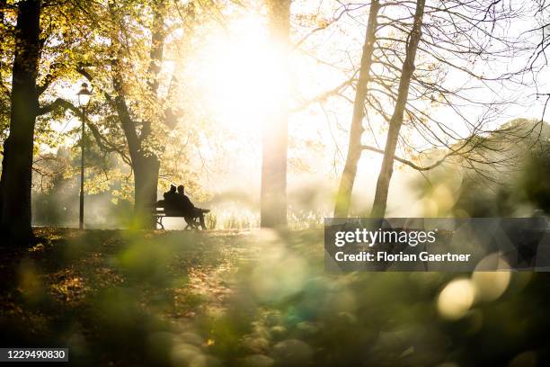 Couple sitting on a bench is pictured during evening light on November 06, 2020 in Chemnitz, Germany.