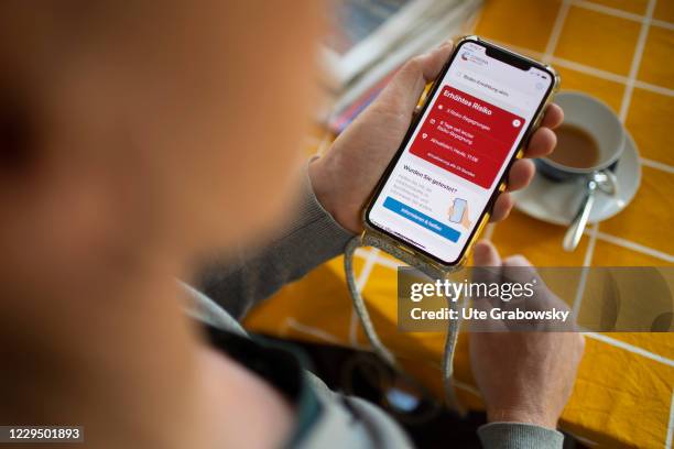 Man looks at his smartphone with a Corona app that displays 3 risk encounters on November 07, 2020 in Bonn, Germany.