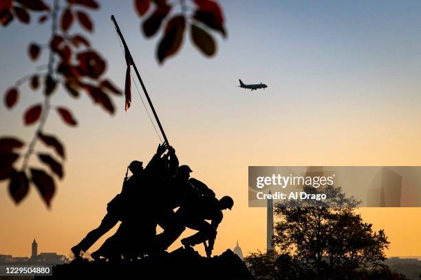 Plane approaches Reagan National Airport as the U.S. Marine Corp's Iwo Jima Memorial can be seen as the morning sun begins to rise behind the U.S....