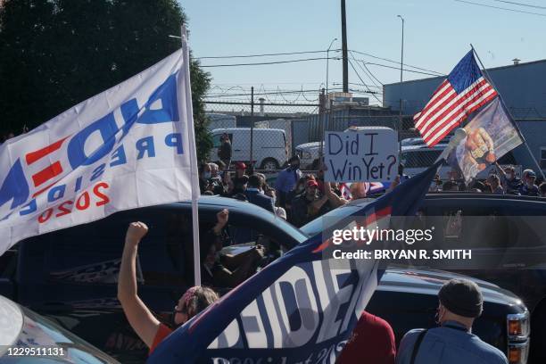 Biden supporters celebrate his victory while Rudy Giuliani speaks at a news conference in the parking lot of a landscaping company on November 7,...