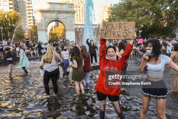 People stand in the fountain as they celebrate in Washington Square Park after it was announced that Democratic nominee Joe Biden would be the next...