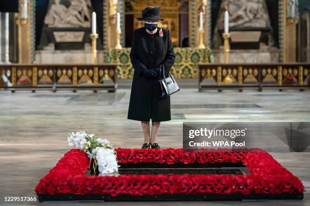 Queen Elizabeth II inspects a bouquet of flowers placed on her behalf at the grave of the Unknown Warrior by her Equerry, Lieutenant Colonel Nana...