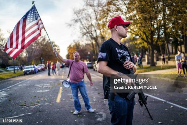 Supporter of US President Donald Trump keeps a hand on his gun during a "Stop the Steal rally" in front of the residence of Minnesota Governor Tim...