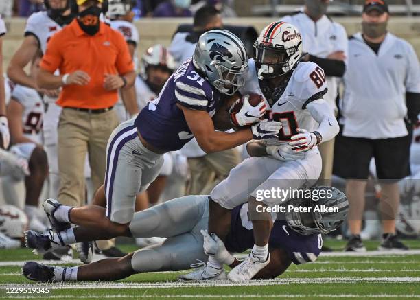Defensive back Jahron McPherson and linebacker Elijah Sullivan of the Kansas State Wildcats tackle wide receiver Brennan Presley of the Oklahoma...