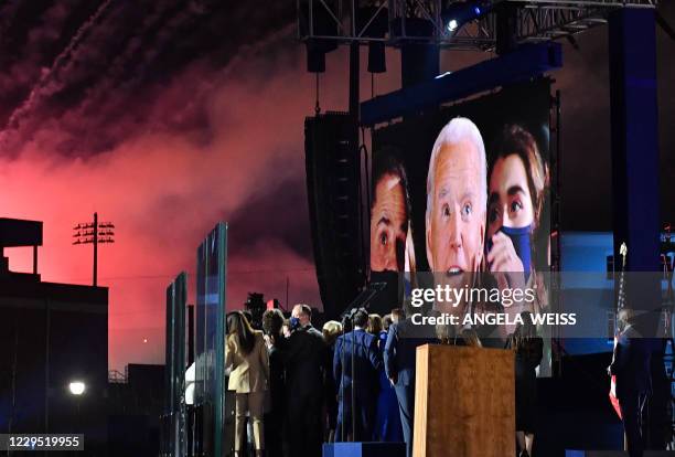 President-elect Joe Biden is seen on a big screen as he, his wife Jill Biden, Vice President-elect Kamala Harris, her husband Douglas Emhoff and...