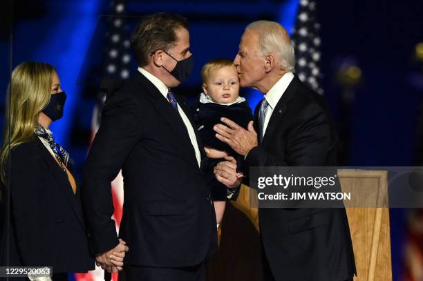 President-elect Joe Biden kisses his grandson held by son Hunter Biden after he and Vice President-elect Kamala Harris delivered remarks in...