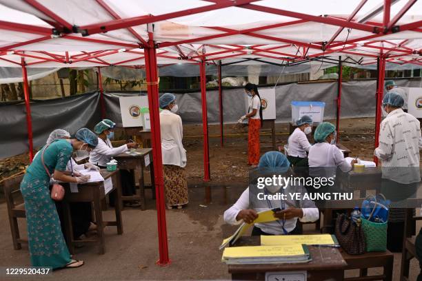 Election officials attend to voters at a polling station in Yangon on November 8, 2020.