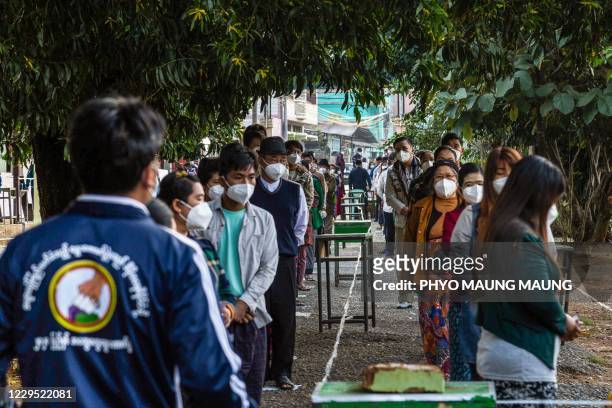 People wearing face masks to prevent the spread of the Covid-19 coronavirus wait to vote at a polling station in Muse, Shan State on November 8, 2020.