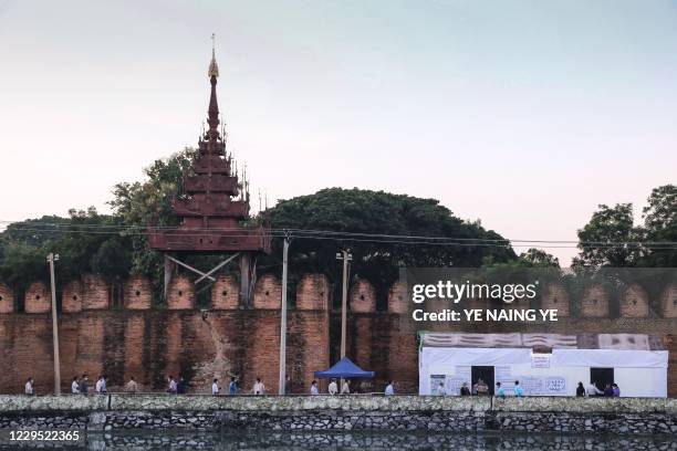 People wait to vote at a polling station next to the royal palace of the last Burmese monarchy in Mandalay on November 8, 2020.