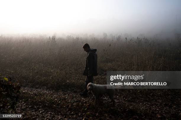 Truffle hunter Carlo Marenda and his dog Buc walk through the Langhe Countryside as they search for white truffles in Roddi, near Alba, north-western...
