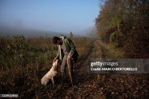 Truffle hunter Carlo Marenda pets his dog Buc as they search for white truffles through the Langhe Countryside in Roddi, near Alba, north-western...