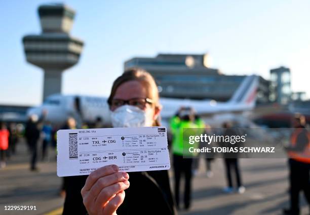 Passenger poses with her ticket from Berlin Tegel to Paris Charles de Gaulle in front the Air France plane before its last take-off from Berlin Tegel...