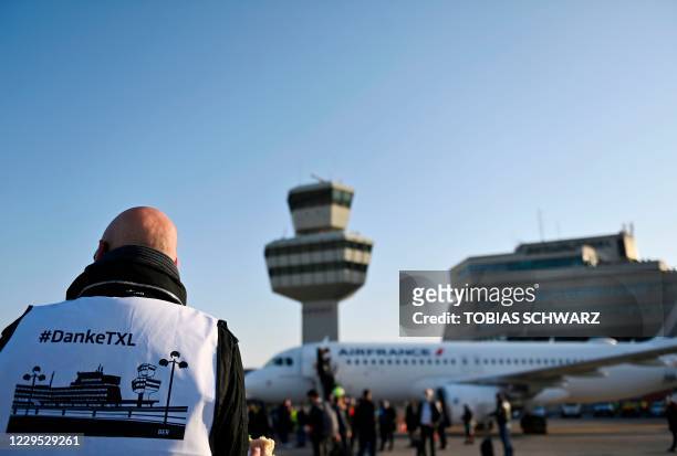 An airport worker wearing a bip reading "thank you Tegel" stands near the Air France plane bound for Paris' Charles de Gaulle airport as it waits on...