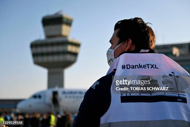 An airport worker wearing a bip reading "thank you Tegel" stands near the Air France plane bound for Paris' Charles de Gaulle airport as it waits on...