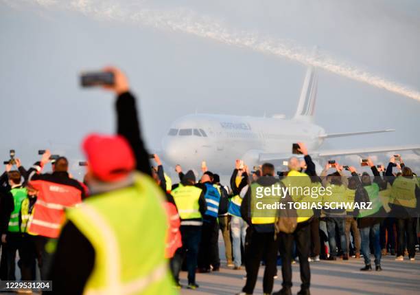 Airport workers take pictures on the tarmac as firefighters spray water on an Air France plane bound for Paris' Charles de Gaulle airport to say...