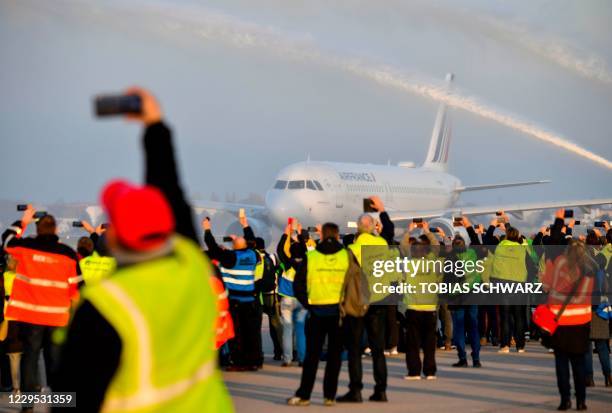 Airport workers take pictures on the tarmac as firefighters spray water on an Air France plane bound for Paris' Charles de Gaulle airport to say...