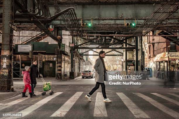 Man passing a cross road with two children behind. Daily life view of the road and street under the subway railroad air-bridge metal construction of...