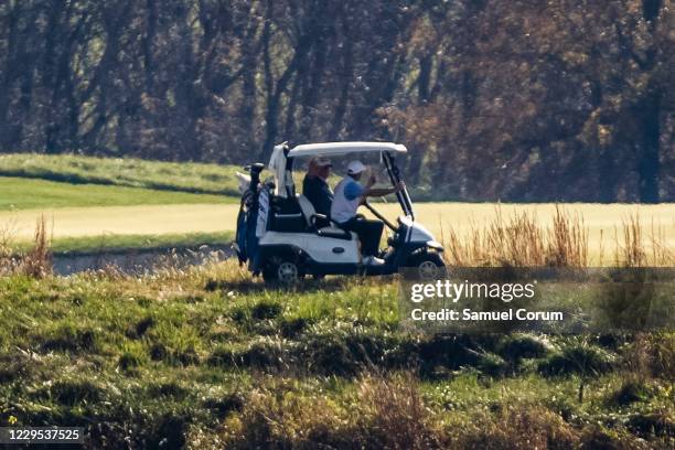 President Donald Trump waves to media across the Potomac River as he plays a round of golf at his private club, Trump National Golf Club, on November...