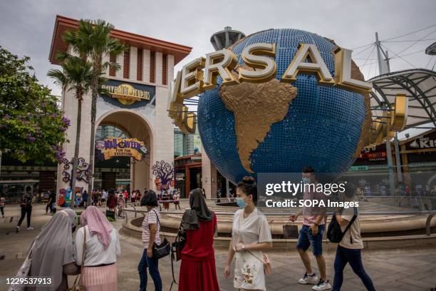 People wearing protective facemasks visit the Universal Studios Singapore in Sentosa, an island situated south from Singapore's mainland.