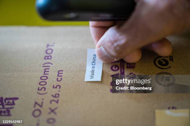 Worker places a "Made in China" label on a case of red vinegar at the Koon Chun Sauce Factory in Hong Kong, China, on Thursday, Nov. 5, 2020. The...