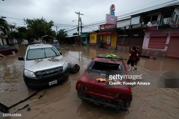 Two women walk down the main street of Colonia Planet lokking at the aftermath left in tropical storm Eta's wake on November 6, 2020 in La Lima,...