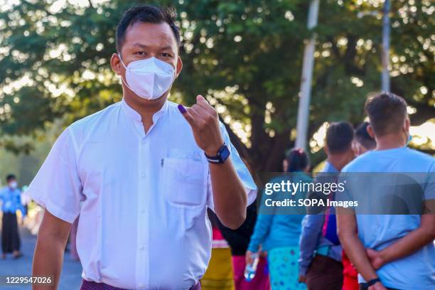 Man wearing a facemask shows off his inked finger after casting his vote at a polling station. Myanmar citizens went out to vote in the second...