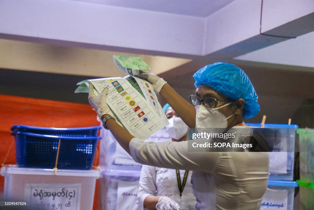 An election officer wearing a facemask counts ballot papers...