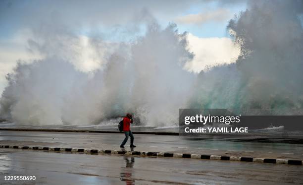 Photographer takes pictures as the sea pounds against Havana's seawall, the Malecon, on November 9, 2020 after the passage of Tropical Storm Eta. -...