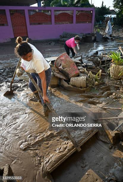 Woman tries to clear the mud from the front of her house as another one salvages belongings in Planeta, municipality of La Lima, in the Honduran...
