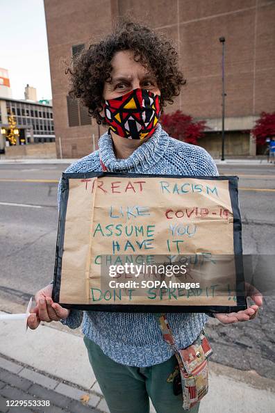 Woman wearing a mask holds a sign likening COVID-19 to Woman wearing a mask holds a sign likening COVID-19 to