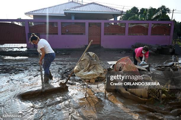 Woman tries to clear the mud from the front of her house in Planeta, municipality of La Lima, in the Honduran department of Cortes, on November 9...