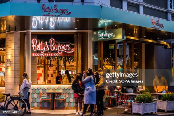 Betty Burgers, fast food outlet with a group of young adults hanging around, bright neon signs on Chapel street, one of the most iconic streets of...